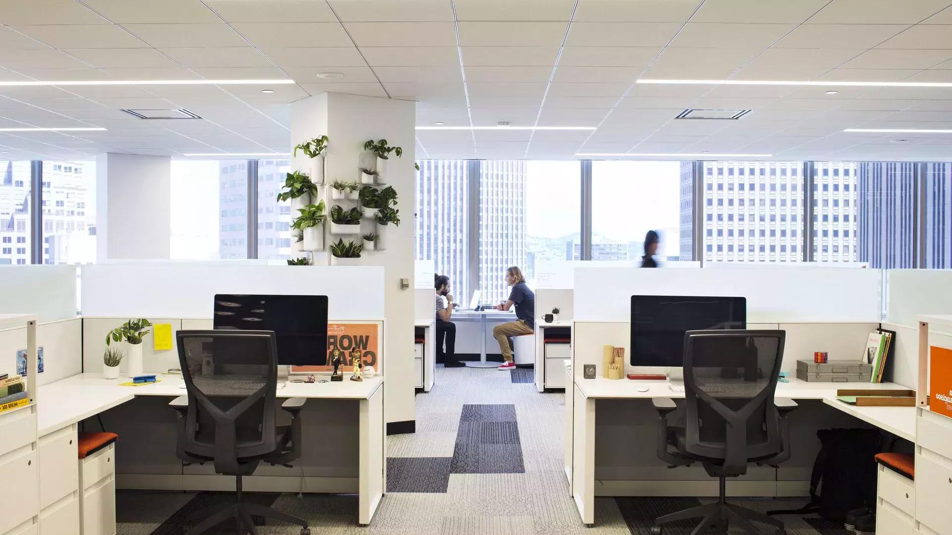 贝博体彩app办公楼的内部场景, 前面有一张桌子，两个人在大窗户前的桌子上工作.