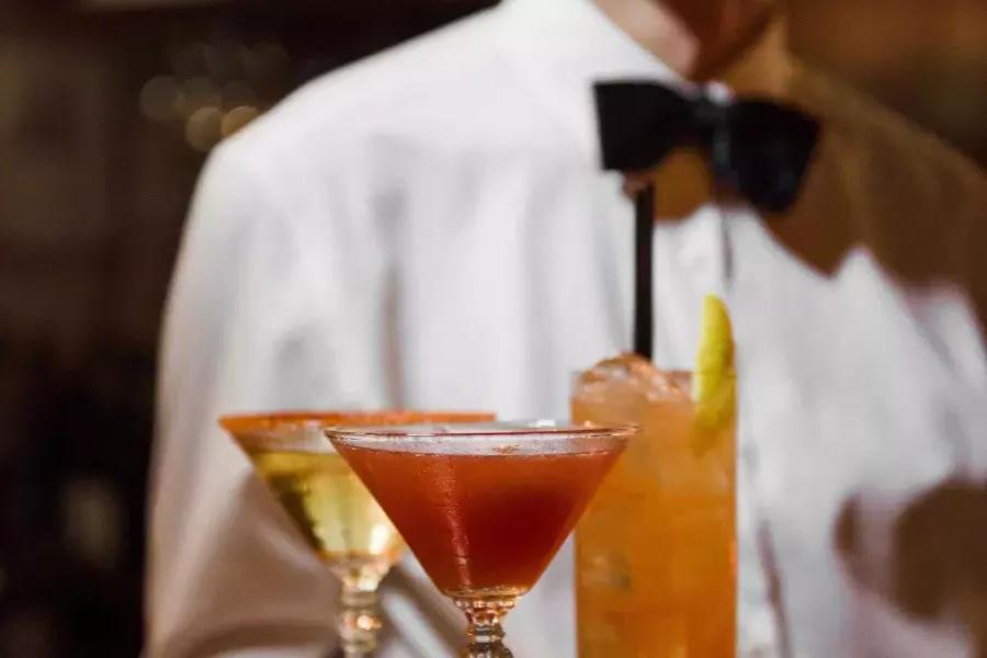 一名打着领结的服务员在贝博体彩app的阿宾斯餐厅(absinthe Restaurant)展示了一盘鸡尾酒.