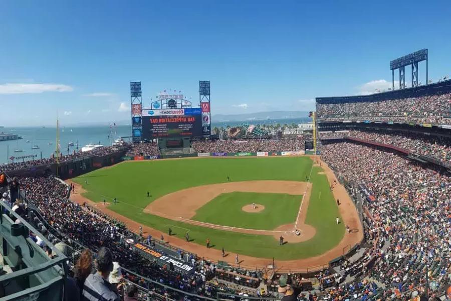 Una vista dell'Oracle Park di San Francisco che si affaccia dagli spalti, con il diamante del baseball in primo piano e la Baia di San Francisco sullo sfondo.