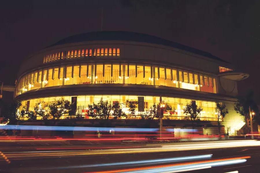 Esterno della Louise M. Davies Symphony Hall di notte con strisce di luce provenienti dai veicoli in transito.