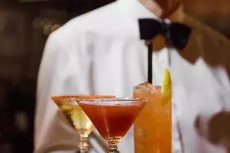 一名打着领结的服务员在贝博体彩app的阿宾斯餐厅(absinthe Restaurant)展示了一盘鸡尾酒.