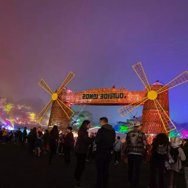 在贝博体彩app郊外的音乐节上，一群参加音乐节的人在夜晚的霓虹灯下拍照.